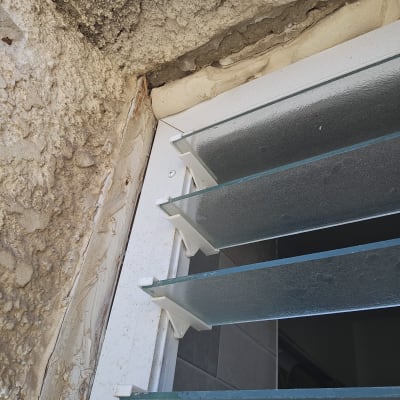 חלון עם תריסים זכוכית וקיר מתקלף