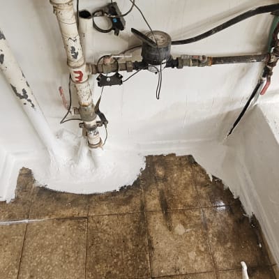 צינורות עם איטום לבן על הרצפה והקיר