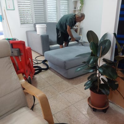 אדם מנקה ספה עם שואב אבק מקצועי