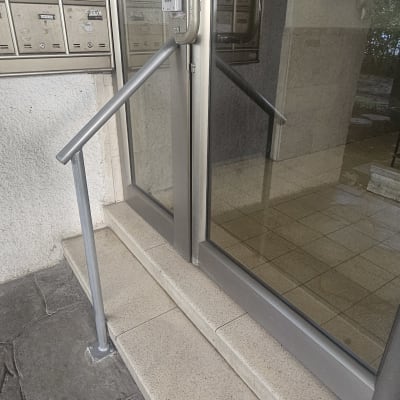 מעקה מתכת ליד דלת זכוכית בכניסה לבניין