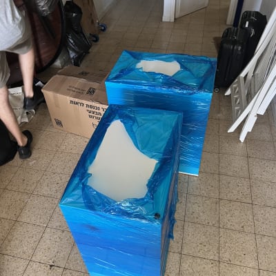 רהיטים עטופים בניילון נצמד כחול וקרטונים המיועדים להובלת דירה