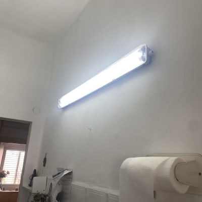 מנורת פלורסנט מוארת על קיר לבן