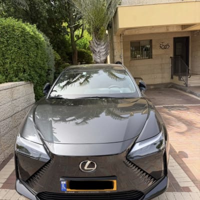 רכב לקסוס חונה ליד בניין עם עצי דקל