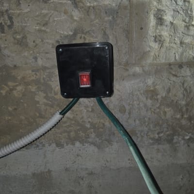 מתג חשמלי מותקן על קיר עם חוטים ירוקים