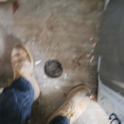 רצפה עם חור ניקוז ונעליים של עובד