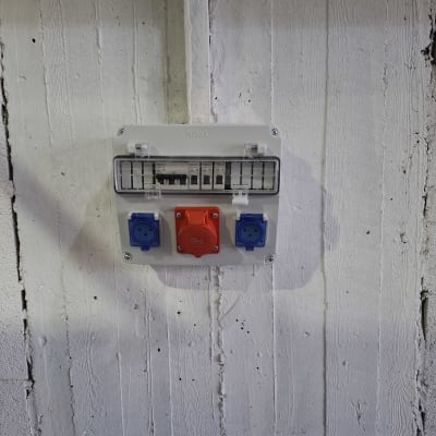 לוח חשמל עם שקעים כחולים ואדום על קיר לבן