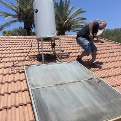 דוד שמש על גג רעפים עם אדם עובד