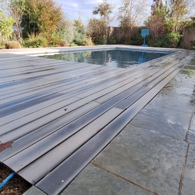 דק עץ ליד בריכה בגינה עם צמחייה מסביב