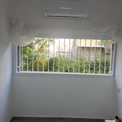 חלון עם סורגים ומזגן מותקן מעליו