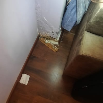 קיר פגום עם סימני רטיבות ליד ספה