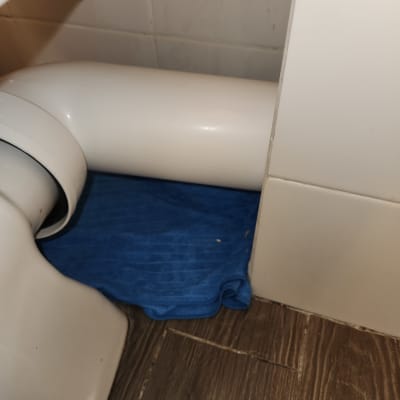 צינור לבן מתחת לכיור עם מגבת כחולה