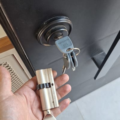 יד מחזיקה צילינדר ליד דלת עם מפתח