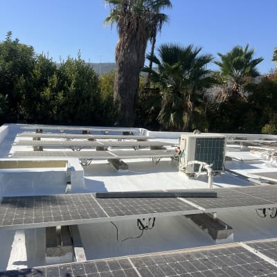 אדם מורח חומר איטום על גג עם פאנלים סולאריים