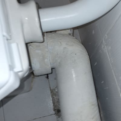 צינור ביוב לבן מחובר לקיר בחדר אמבטיה