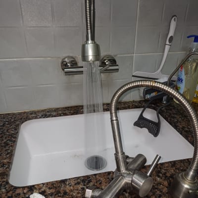 ברז מים זורם בכיור מטבח עם כלים