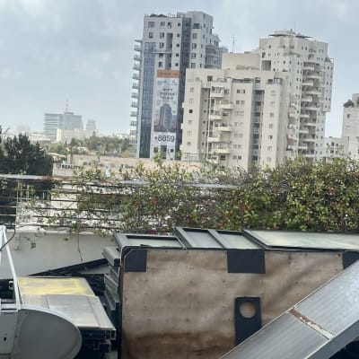 בניינים גבוהים עם פרסומת על אחד מהם, צלחות לוויין על הגג.