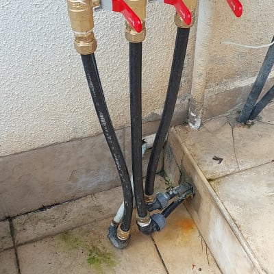 ברזים עם ידיות אדומות וצינורות שחורים מחוברים לקיר