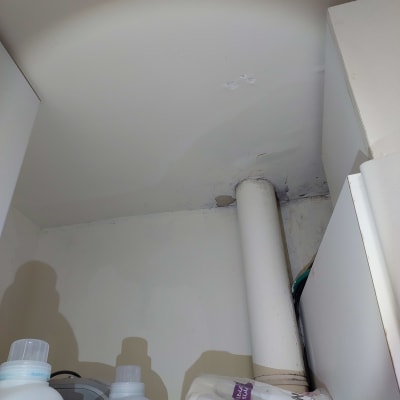 תמונה של צינור ונזילה בתקרה, מוצרים לניקוי נראים בתחתית
