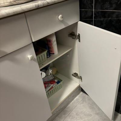 ארון מטבח פתוח עם מוצרי ניקוי וסלסלות אחסון