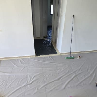 חדר עם יריעות פלסטיק על הרצפה ומטאטא בצד