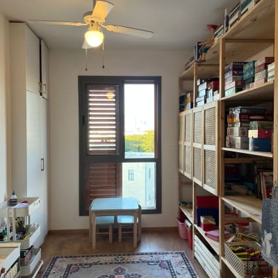 מדפים עם משחקים וצעצועים, שולחן קטן, שטיח צבעוני