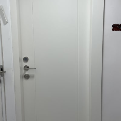 דלת לבנה עם ידית מתכת ועיטור מסגרת