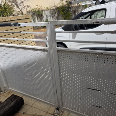 שער חשמלי עם מנוע ליד רכב לבן