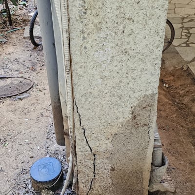 עמוד בטון עם סדק בחוץ ליד צינורות