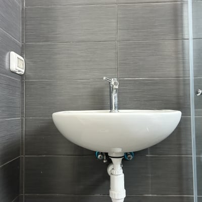 כיור תלוי על קיר עם ברז וכיור לבן