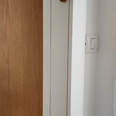 מתג חשמל על קיר לבן ליד דלת עץ