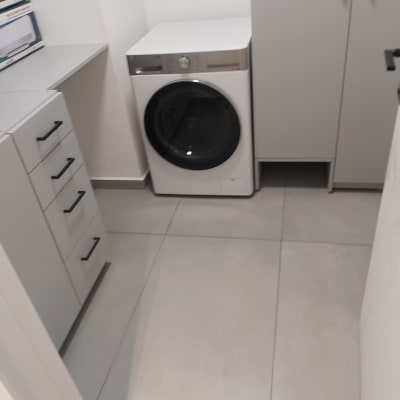 מכונת כביסה בחדר כביסה עם ארונות אפורים