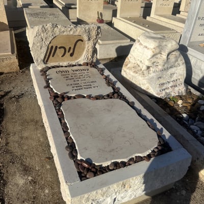 מצבה עם כיתוב בעברית ואבנים מסביב