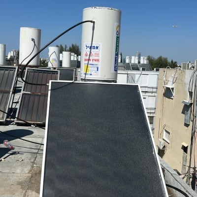 דוד שמש וקולטים על גג תחת שמיים כחולים