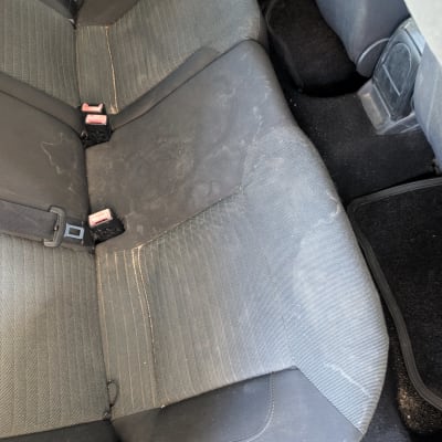 מושבי בד אחוריים של רכב המציגים לכלוך וכתמים לפני ניקוי ריפודים