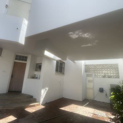 חצר עם קירות לבנים וצמחייה, צינור מים על הרצפה