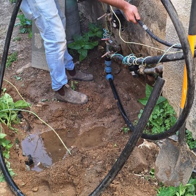 אדם עובד על צינורות מים עם כלים בחוץ