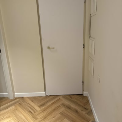 דלת לבנה עם ידית מתכת על רקע קיר בהיר