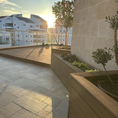 גינה מעוצבת עם דק עץ וצמחים על מרפסת