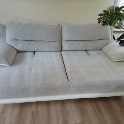 ספה אפורה בחדר מגורים עם צמח ירוק ליד