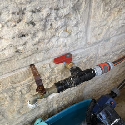 ברזים וצינורות ליד קיר אבן עם משאבה