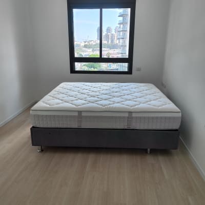 חדר ריק עם מיטה ומזרן על רצפת עץ