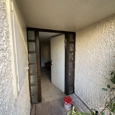 דלי צבע אדום בכניסה לבית עם דלת פתוחה