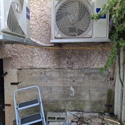 שני מזגנים מותקנים על קיר חיצוני עם סולם קטן.