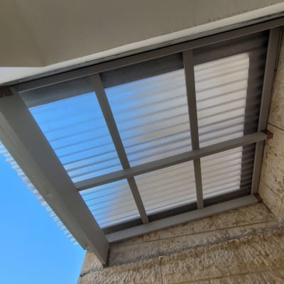 גג פרגולה עם קורות מתכת ולוחות שקופים