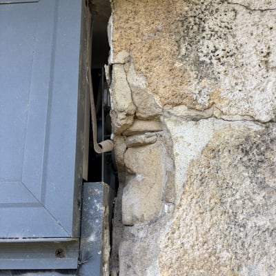 קיר אבן עם סדקים ונזק ליד חלון מתכת