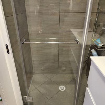 מקלחון עם דלת זכוכית ומוט מתכת