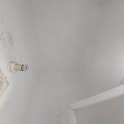 מנורה מותקנת על קיר לבן עם סימני תיקון