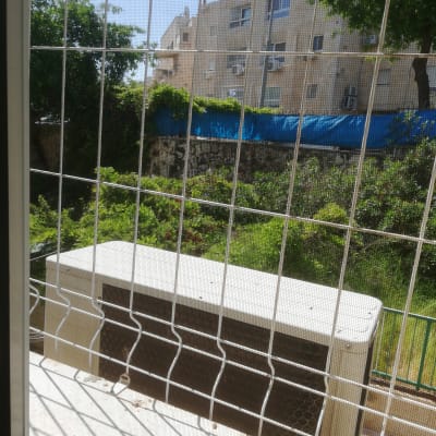 סורגי אלומיניום על חלון עם נוף חיצוני