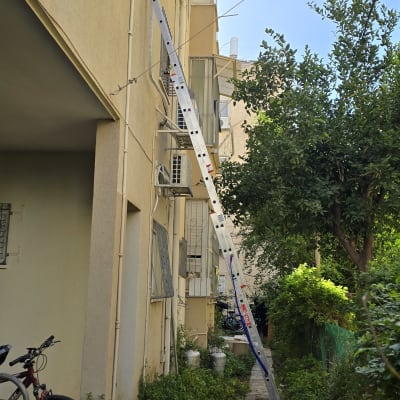 סולם ליד בניין עם מזגנים מותקנים על הקיר החיצוני