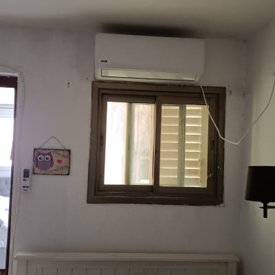 מזגן מותקן מעל חלון בחדר שינה